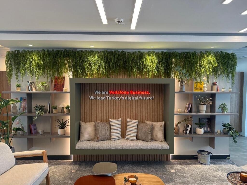 Lounge mit begrünter Wand und rotem Markenakzent