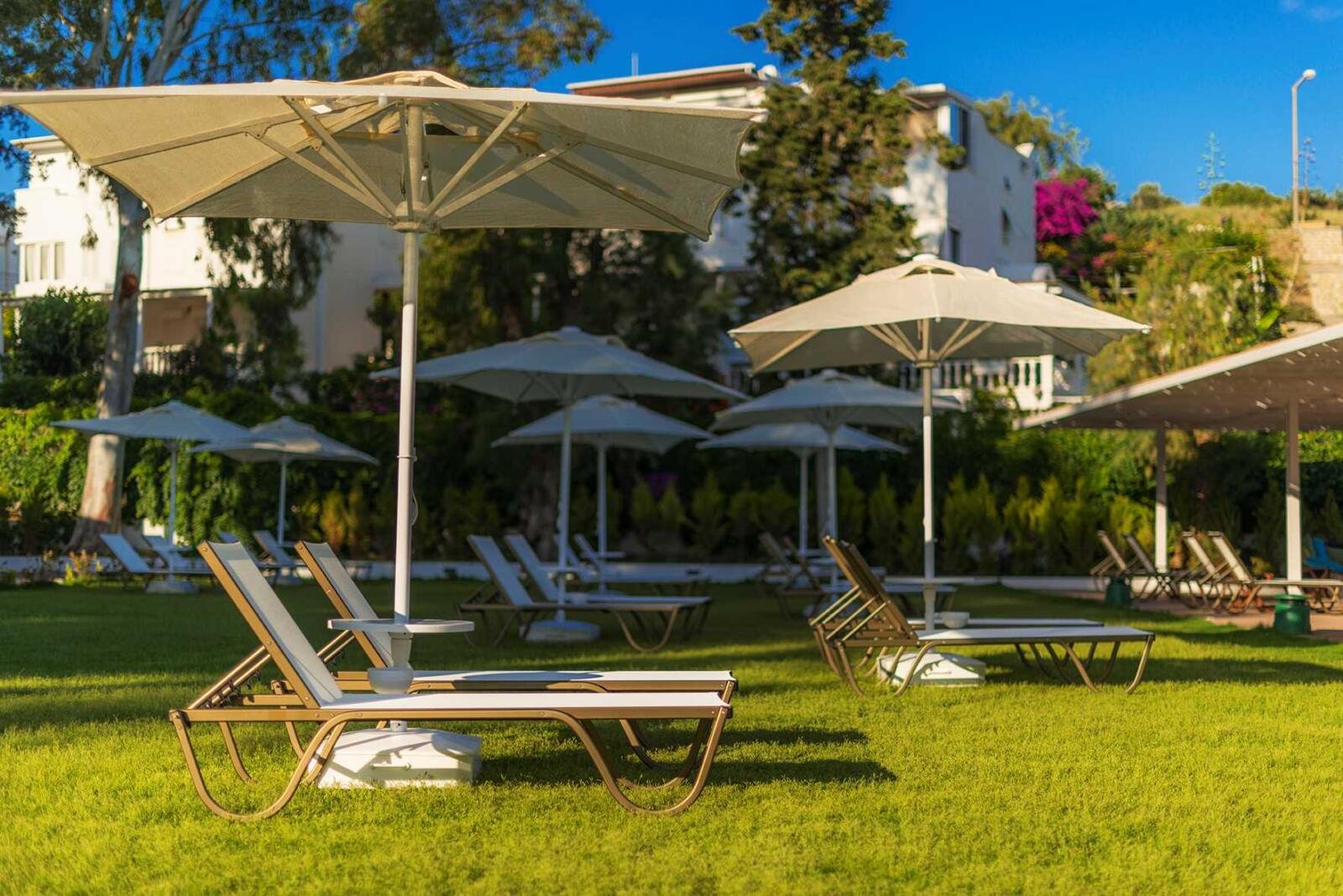 Hotelrenovierung Bodrum mit gepflegtem Garten, Sonnenliegen und schattigen Aufenthaltsbereichen.