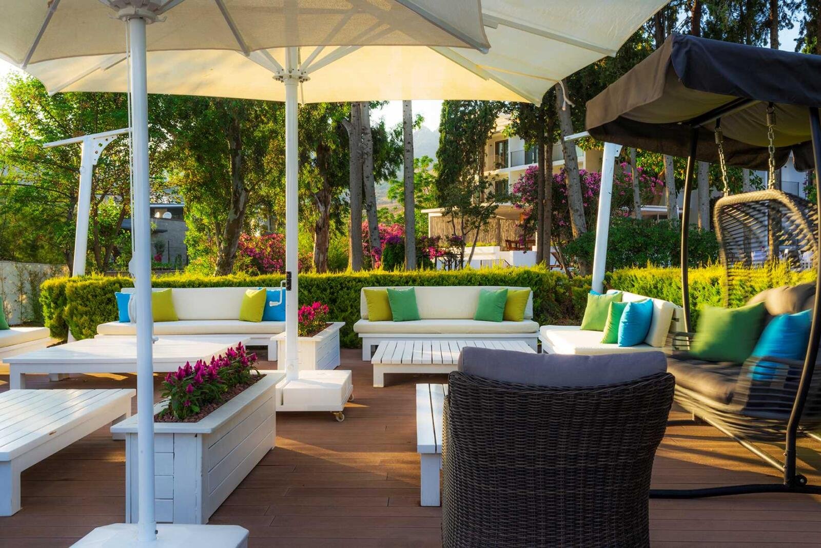 Überdachter Lounge-Bereich des LIV Hotel by Bellazure mit Sitzgruppen und Gartenblick.