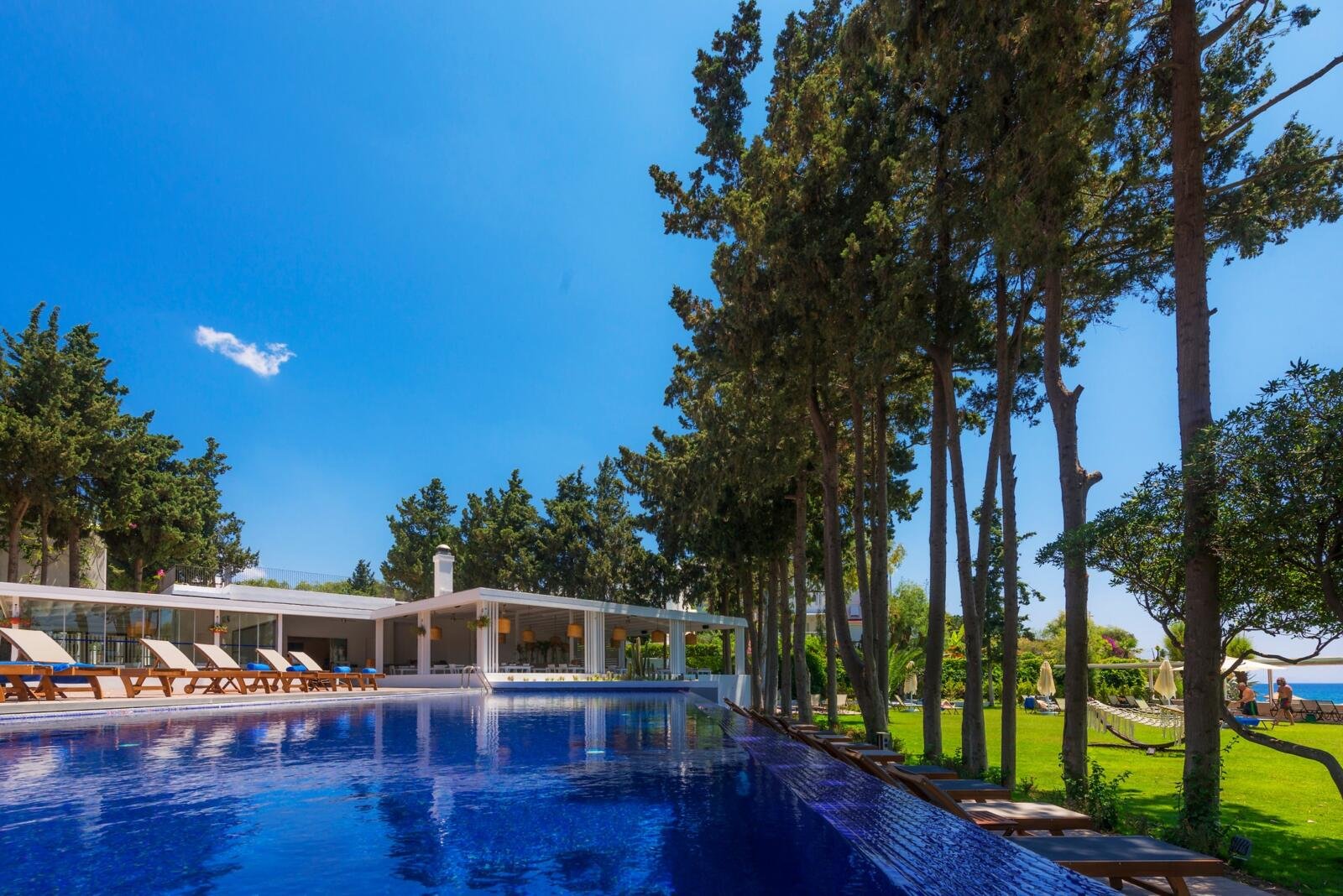 Poolanlage des LIV Hotel by Bellazure mit Blick auf das Meer und die Küstenlandschaft.